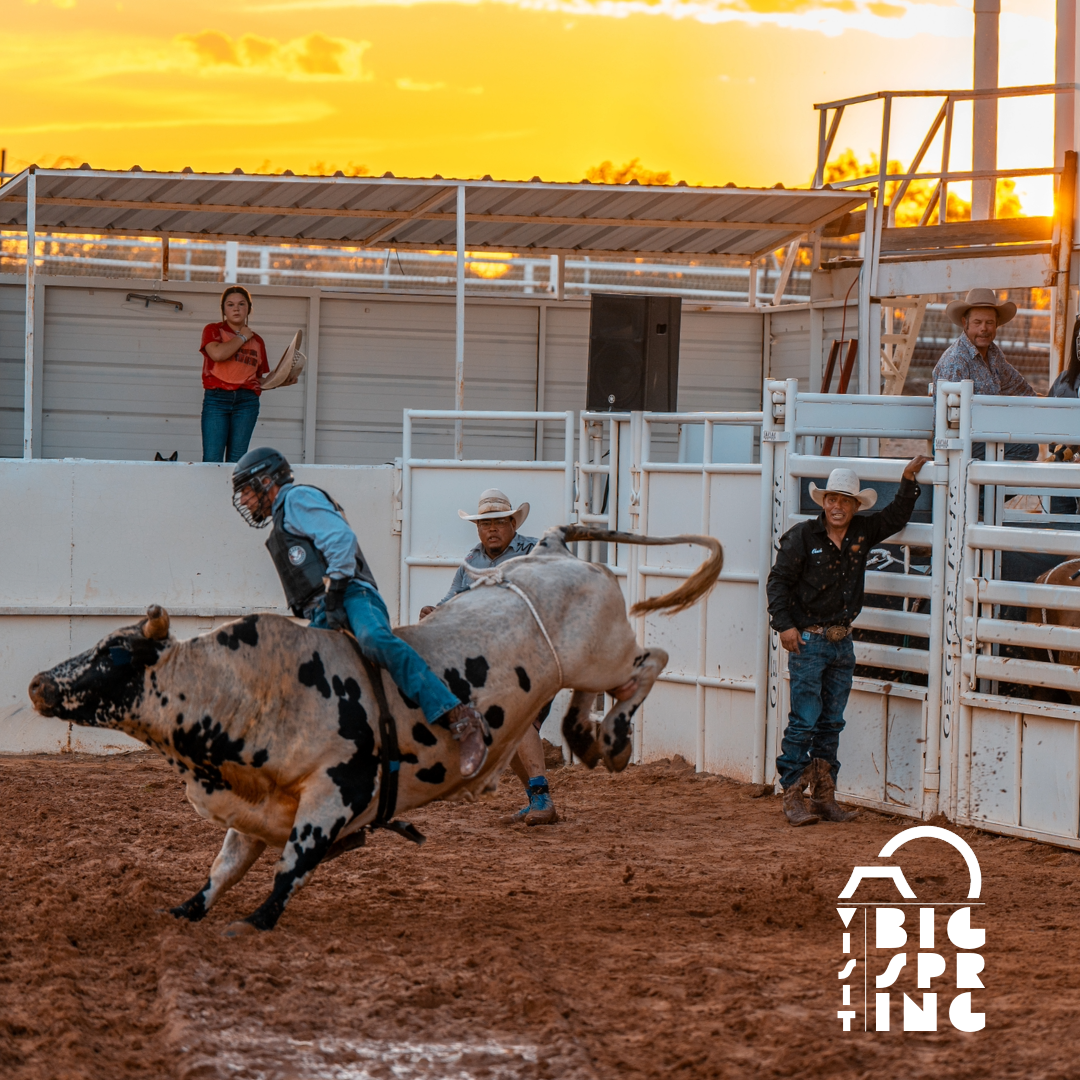 A Cowboy fiercely rides a bucking bull on the backdrop of a dramatic Sunset in Big Spring, TX.