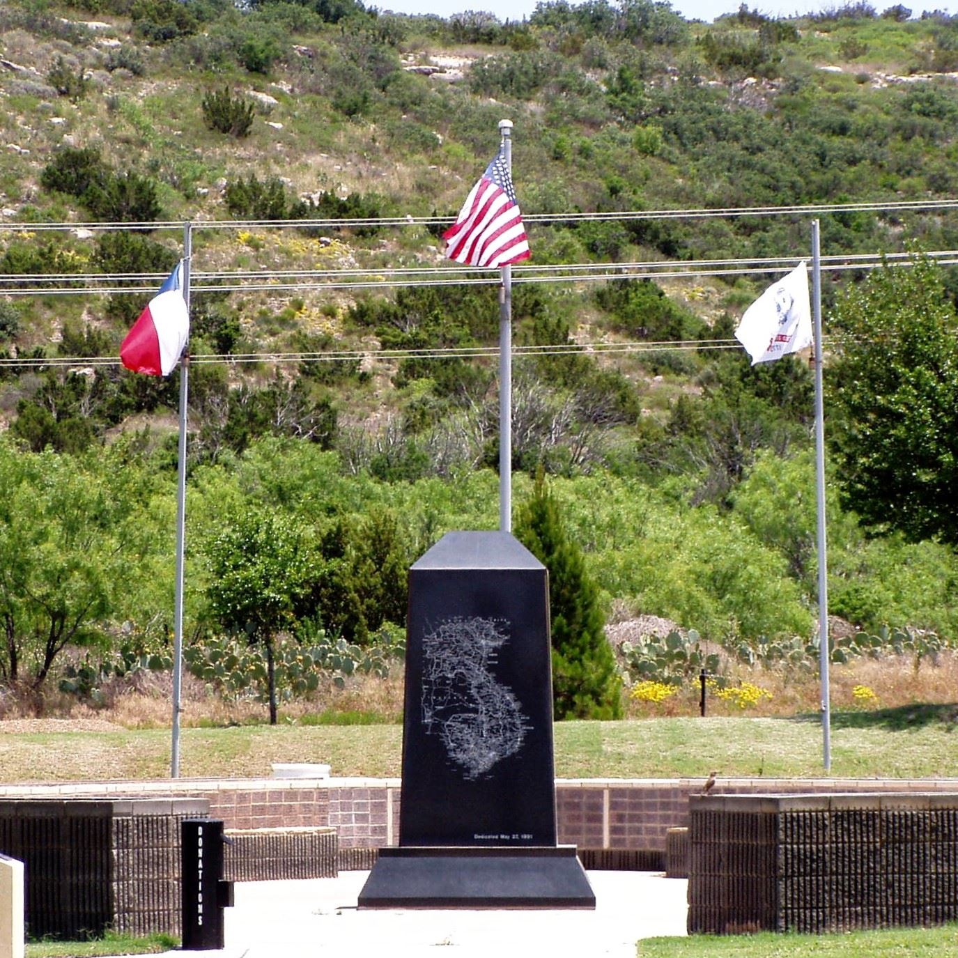 Vietnam War Memorial in Big Spring, Texas, with American, Texan, and POW/MIA flags flying behind.